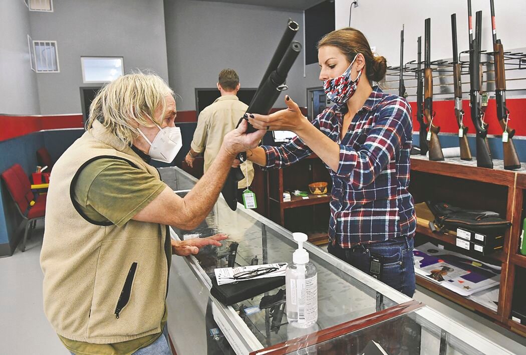 Long Shot Inc. Assistant Manager Brianna Keller, 33, chats with Yelm customer John Chambers, 67, on Thursday, Aug. 6, about purchasing a rifle.