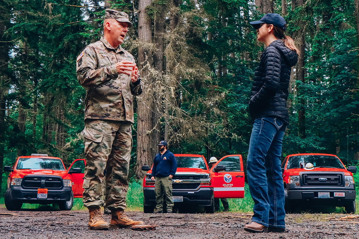 FILE PHOTO — General Dan Dent of the Washington Army National Guard talks with state Commissioner of Public Lands Hilary Franz in 2019 at Joint Base Lewis McChord.