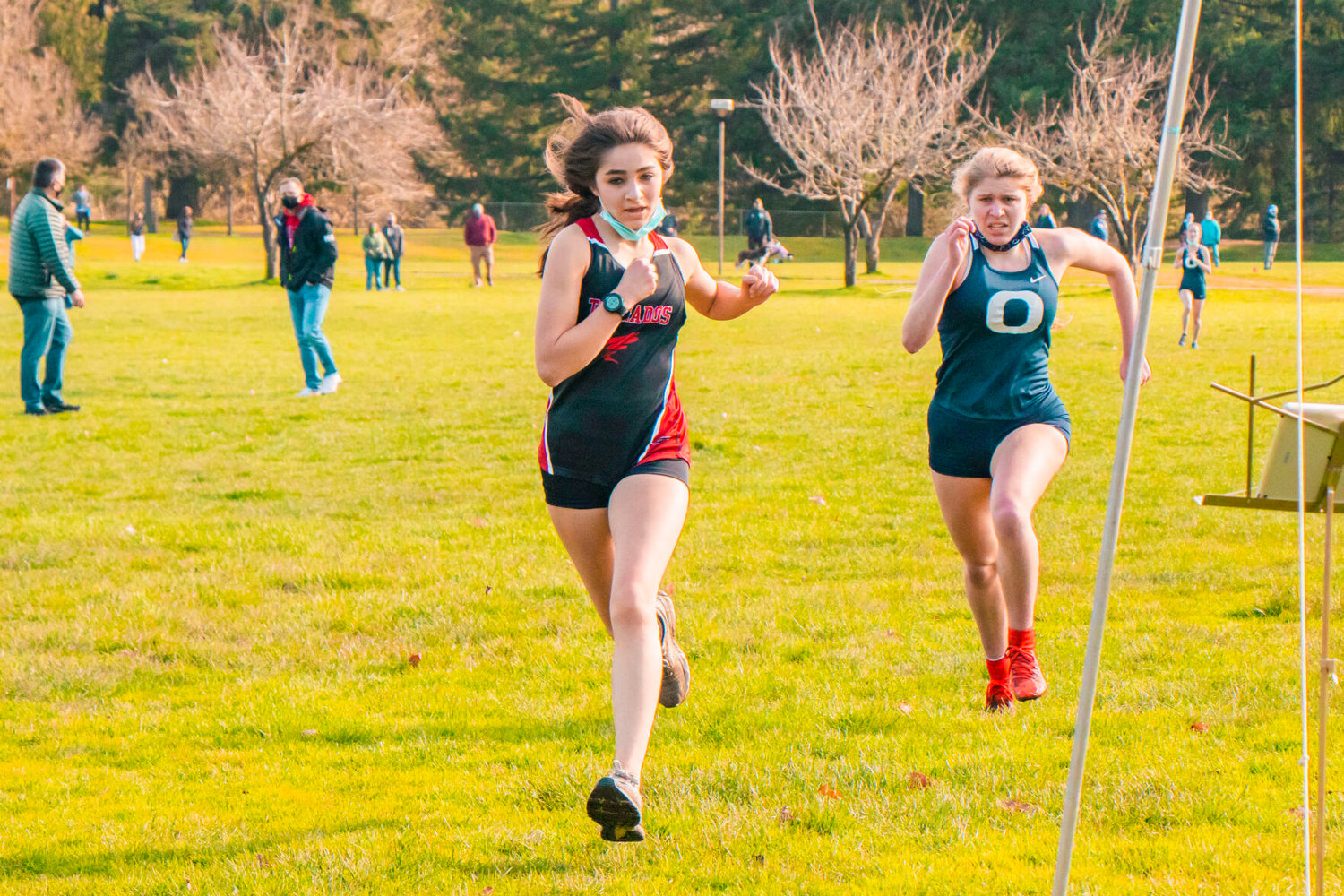 Yelm’s Sophia Laughlin, a freshman, and Olympia’s Elsa Wirth run to the finish line at LBA Park during a cross-country meet in Olympia on Saturday.