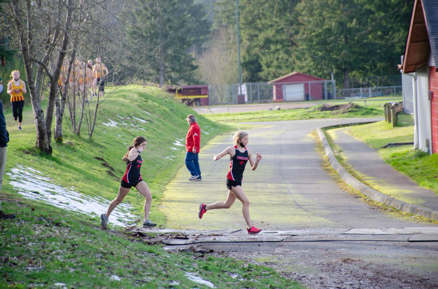 Yelm's Kya Ramirez and Sophia Laughlin, both leading, cross onto Capital's track and field Wednesday during a meet against the host team. 