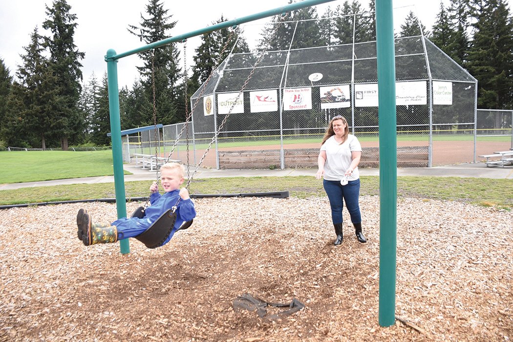 Aiden Thomas swings as his mom, Lisa Thomas, watches at Longmire Park last year.