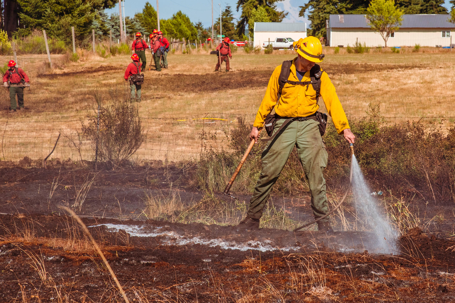 A Department of Natural Resources firefighter uses a hose to extinguish hot spots along the northbound lane of Interstate 5 on Wednesday.