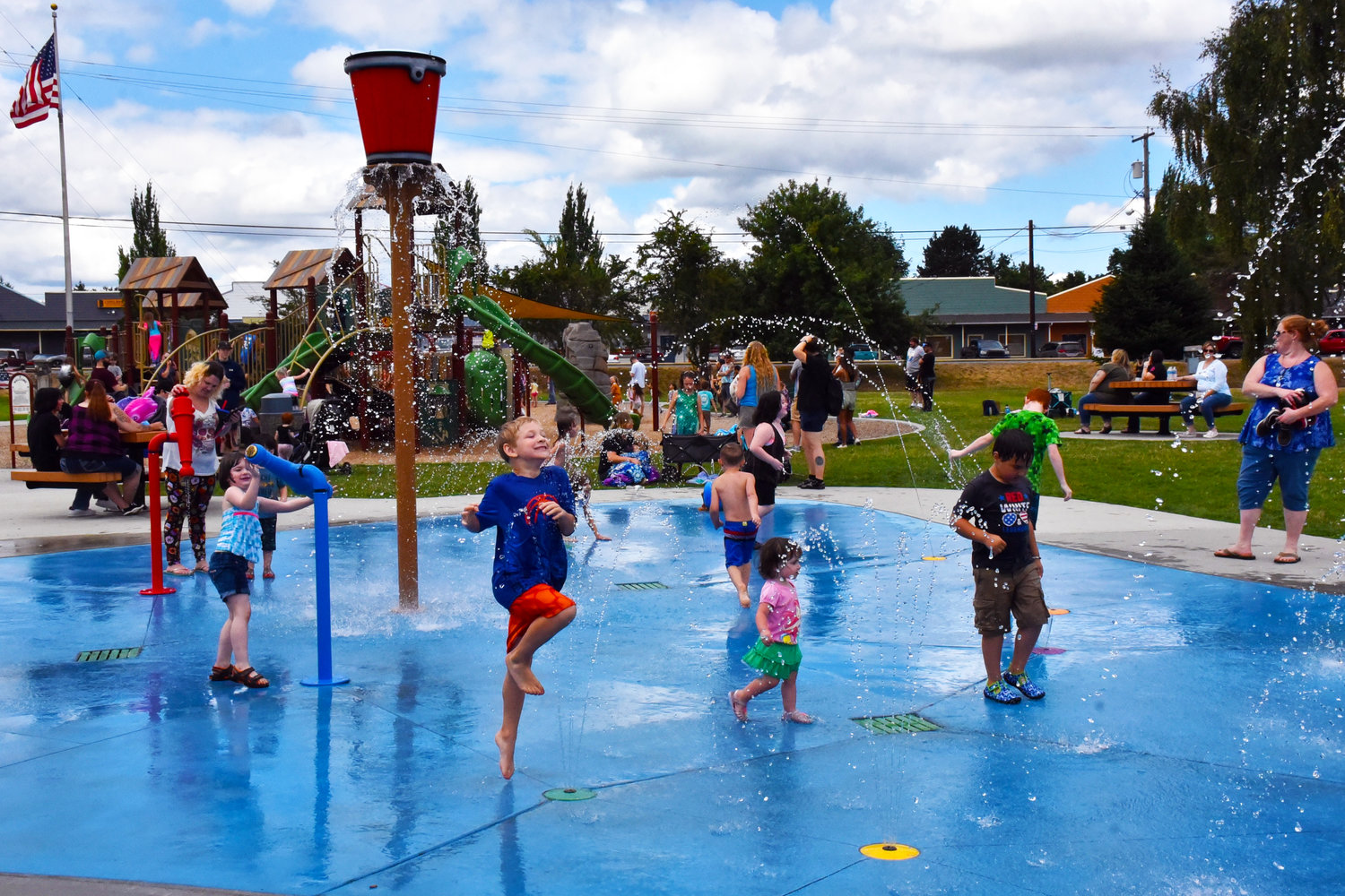 Kids flip their fins through the splash pad at Yelm City Park during the 2021 Yelm Mermaid Festival on Saturday, July 17, an event where 3,900 people came smimming through.