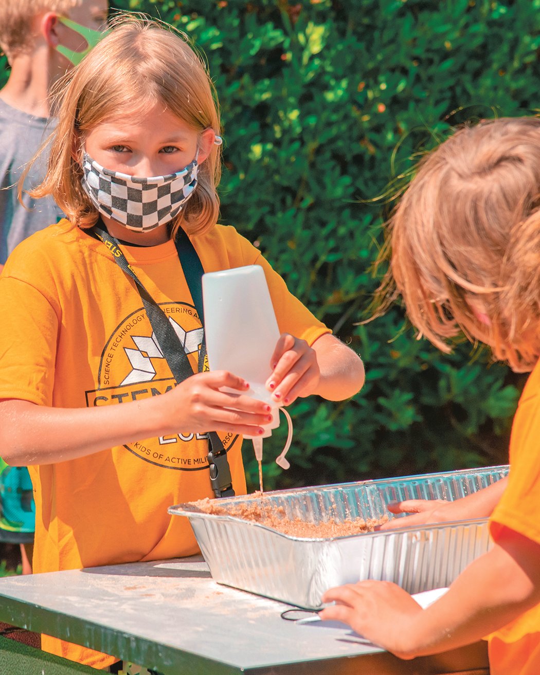Students learn about erosion at Ridgeline Middle School in Yelm during STEMKAMP as they control the amount of water flowing through sand in aluminum bins on Thursday, Aug. 12.