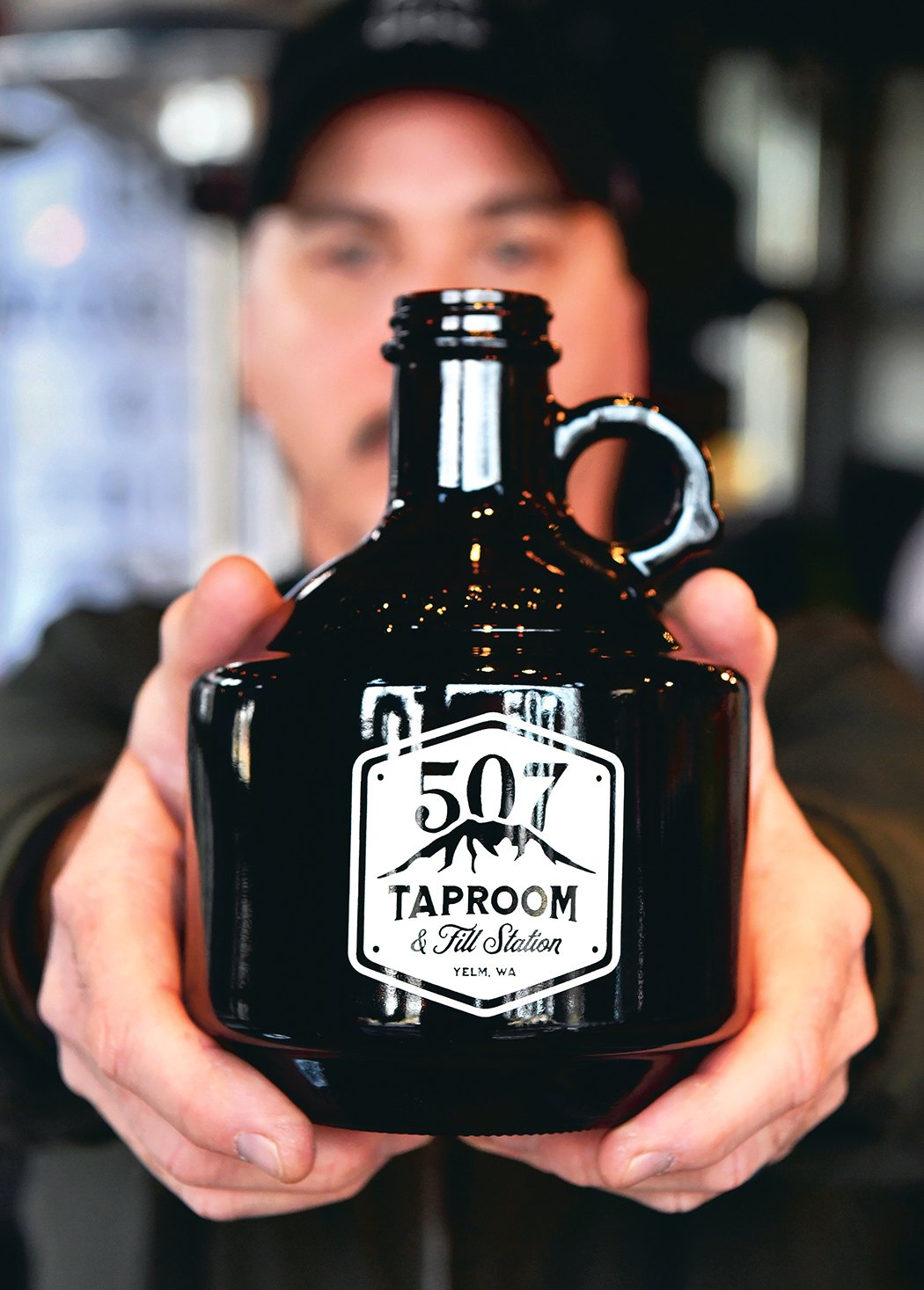 Bill DeVore, who owns 507 Taproom and Filling Station in Yelm, displays a 32-ounce "growler" to-go bottle at the business in this file photo.