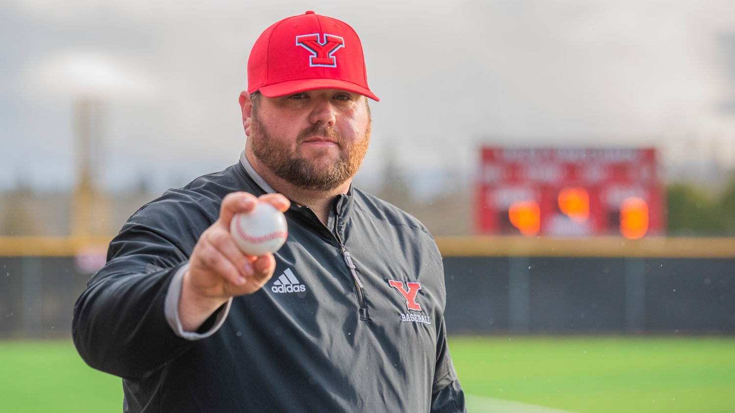 Tornado Baseball Coach Zach Miller holds up a game ball during a game on Tuesday, March 15. Miller, a Yelm High School graduate, played in the program from 2002 to 2006.