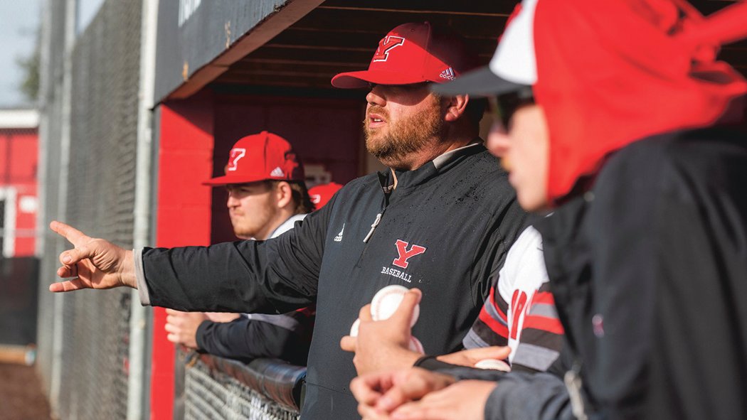 Tornados baseball coach Zach Miller signals to athletes during a game earlier this season.