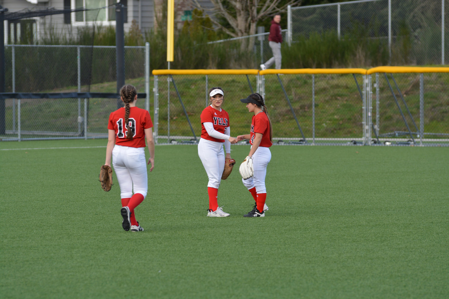 The Yelm outfield meets in between outs on Friday, March 25 at Bellevue College.