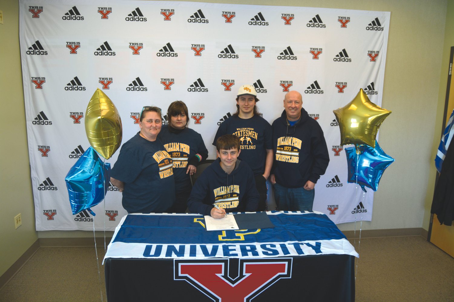 Jeffrey Myers, joined by his family, poses for a picture before he signed his National Letter of Intent to wrestle at William Penn University.