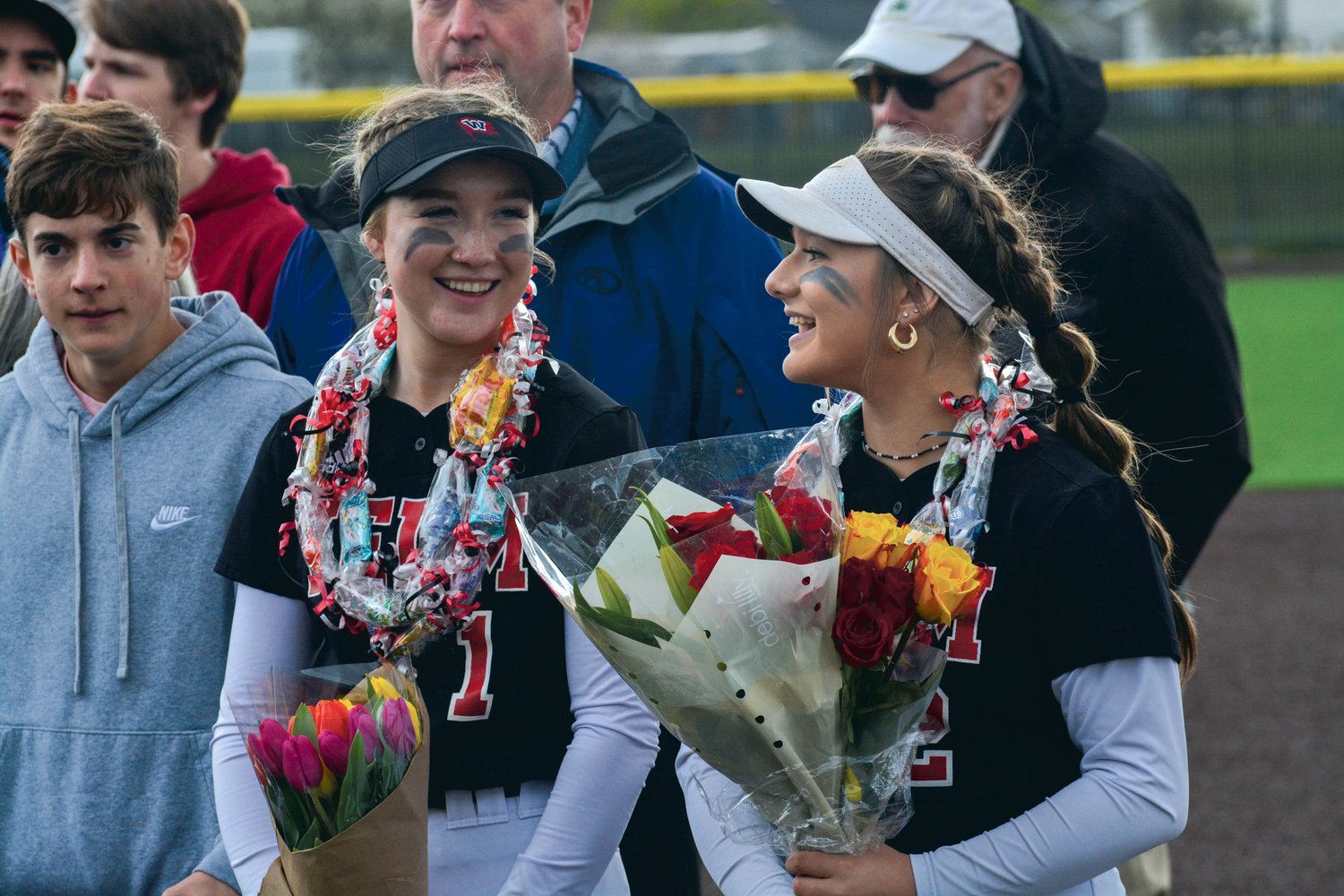 Seniors Molly Embrey (left) and Elena Castanon (right) smile after they received flowers on senior night on May 9 following a game against Capital High School.