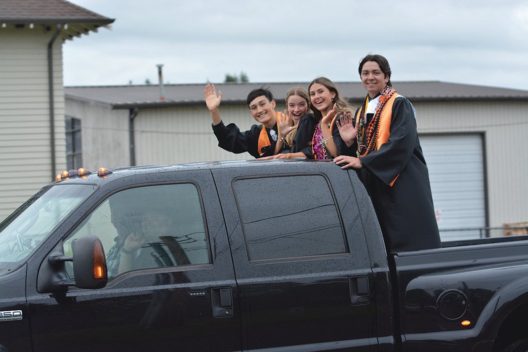 Four Rainier graduates wave and smile on June 10 during a parade that followed their graduation ceremony.