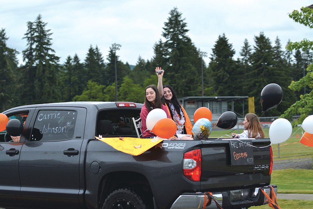 Rainier graduate Carrie Johnson displays a “kiss my class goodbye” sign during a parade on June 10.