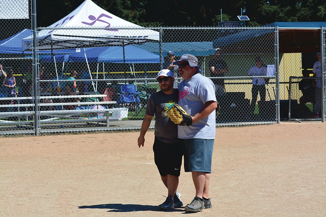 Yelm’s Mayor Joe DePinto embraces former Yelm Chief of Police Todd Stancil, who threw out the celebratory first pitch during the second annual mushball tournament on June 26.