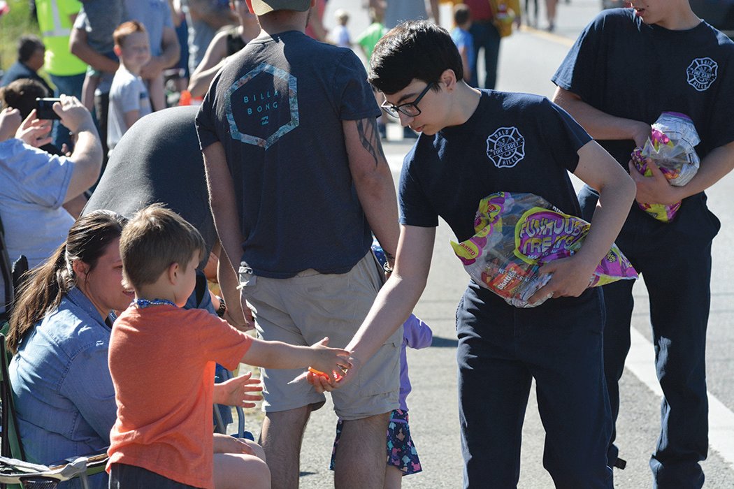 A Bald Hills fire cadet gives candy to a young parade watcher.