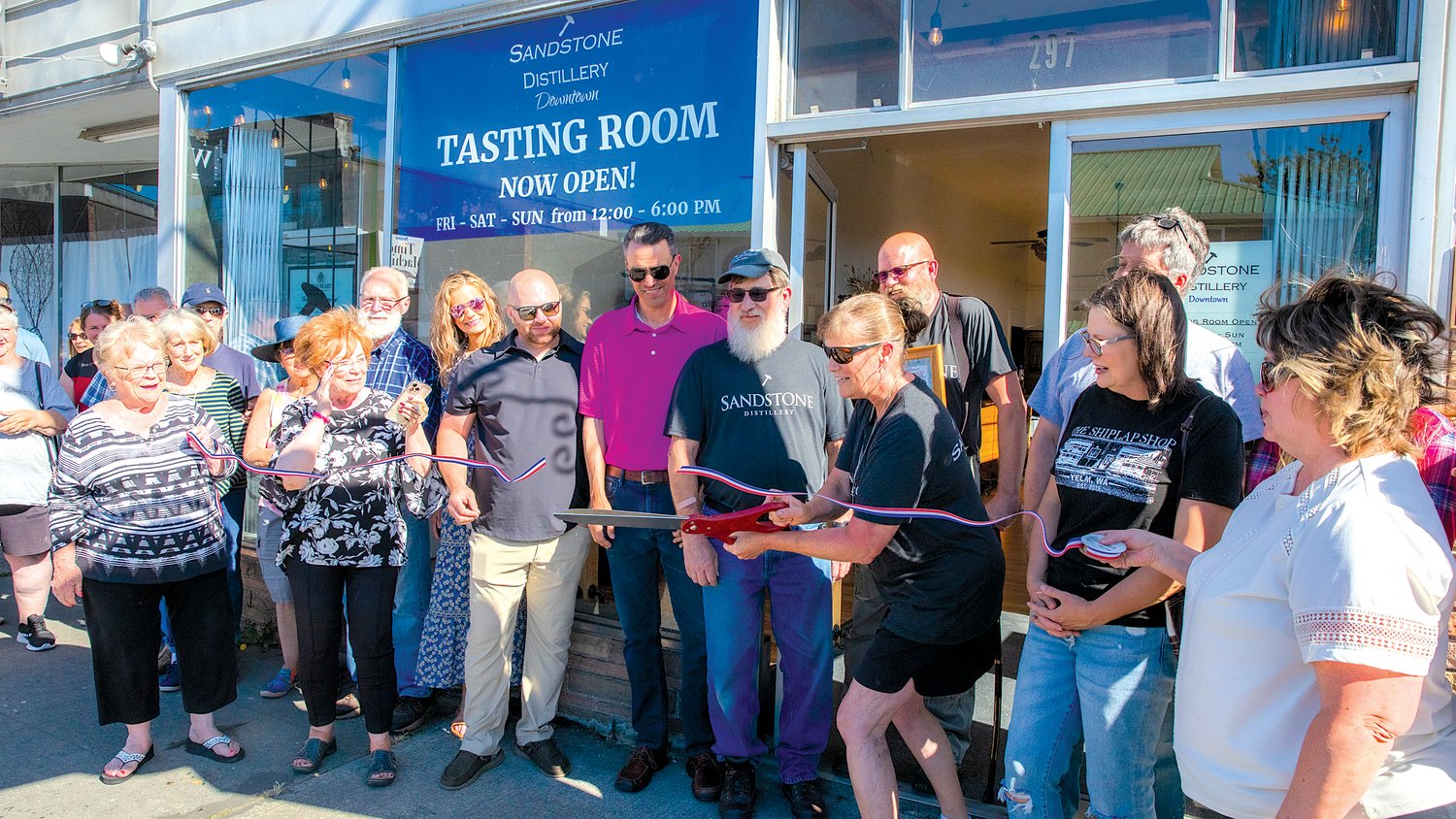 Jenni Bourdon smiles as she cuts a ribbon during a ceremony for the opening of the Sandstone Distillery Tasting Room in downtown Tenino on Thursday. The new tasting room is located at 297 Sussex Ave. W. in Tenino. The room will be open Saturday and Sunday for Oregon Trail Days. Learn more by following the Sandstone Distillery on Facebook.