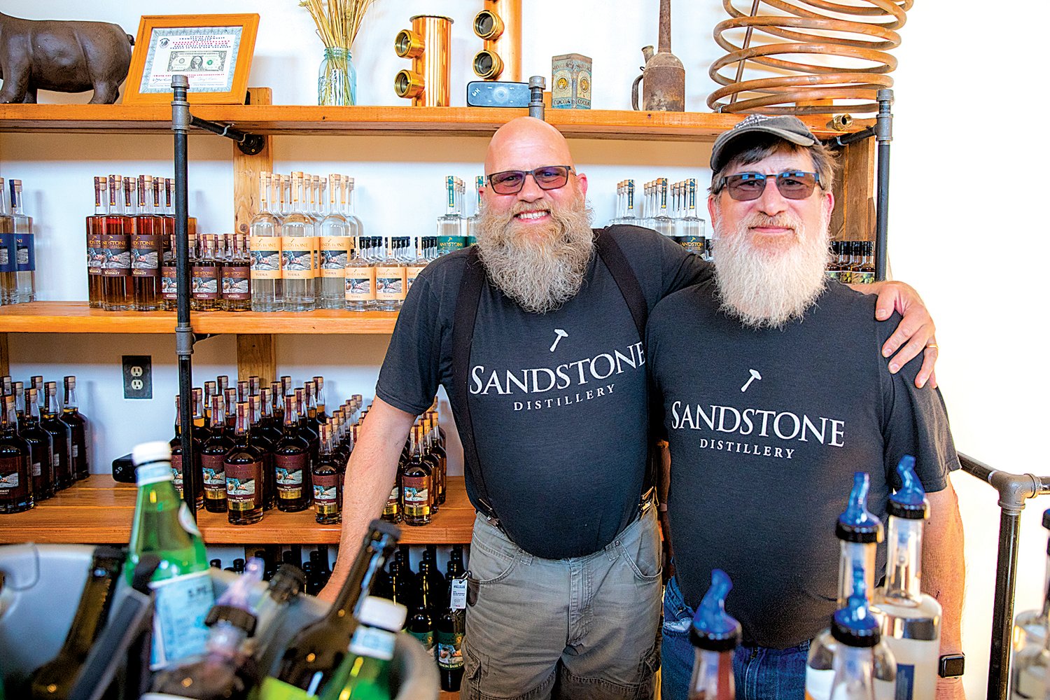 John Bourdon smiles alongside Randy Rawson behind the bar in the Sandstone Distillery Tasting Room on Thursday in downtown Tenino.