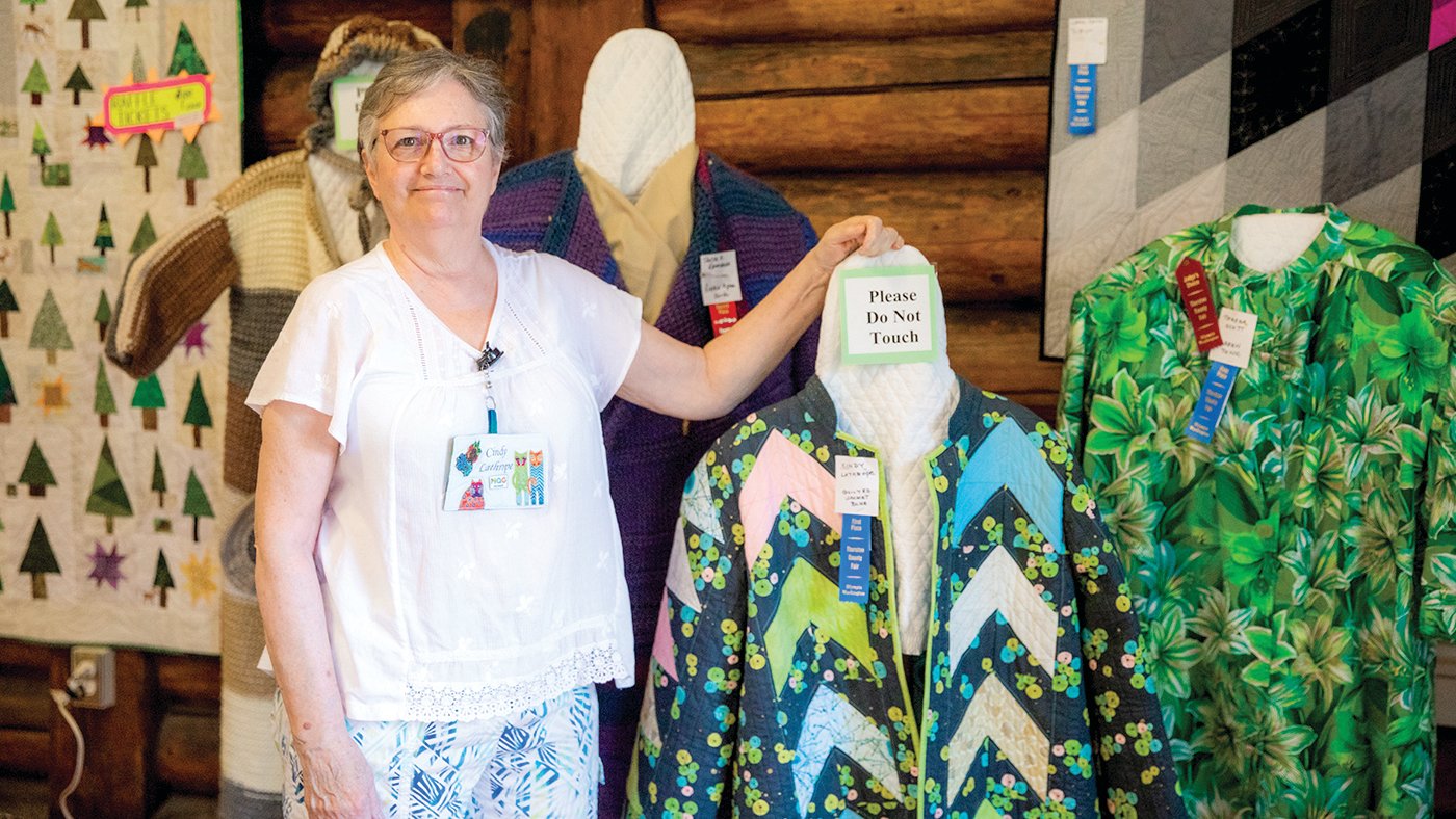 Cindy Lithrope, of Tenino, poses for a photo next to a coat she designed during the Thurston County Fair on Thursday, July 28.