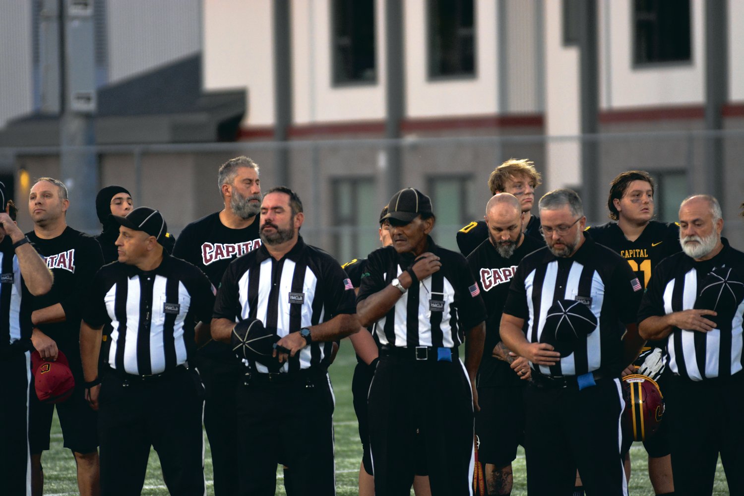 Officials pay their respects during a moment of silence for Mike Kain at Ingersoll Stadium on Sept. 29.
