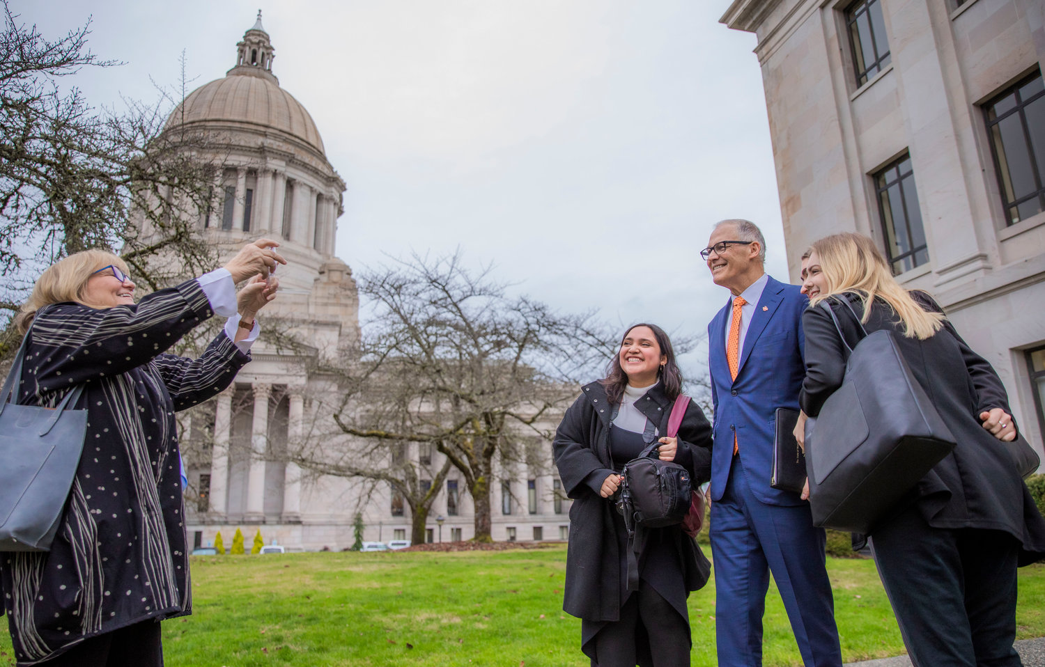 Trudi Inslee smiles while taking photos of Gov. Jay Inslee next to fans on Thursday, Jan. 5, outside the John A. Cherberg Building in Olympia.