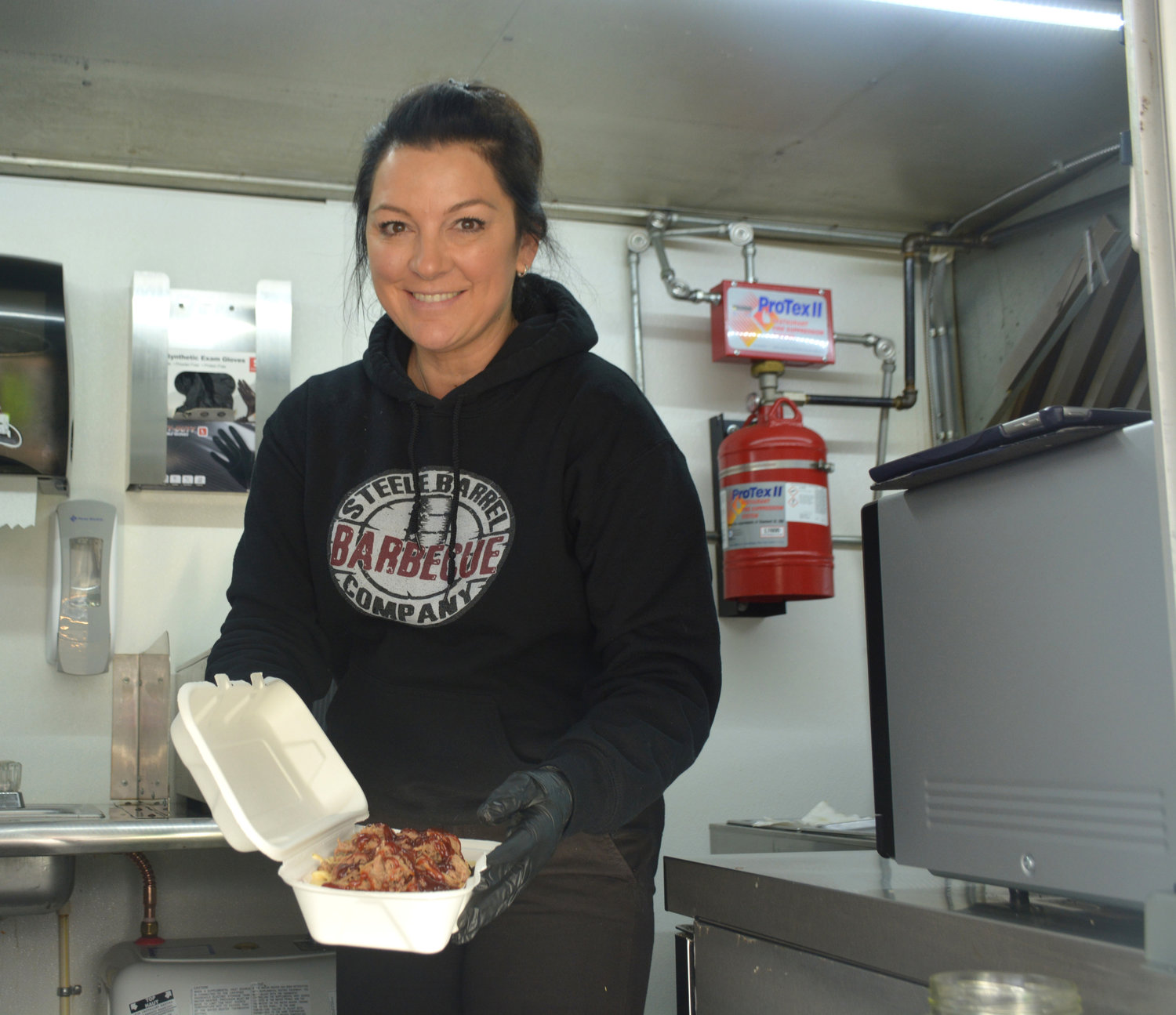 Ksea Clayton shows off a serving of the loaded mac and cheese at the Steele Barrel Barbecue truck in Yelm.
