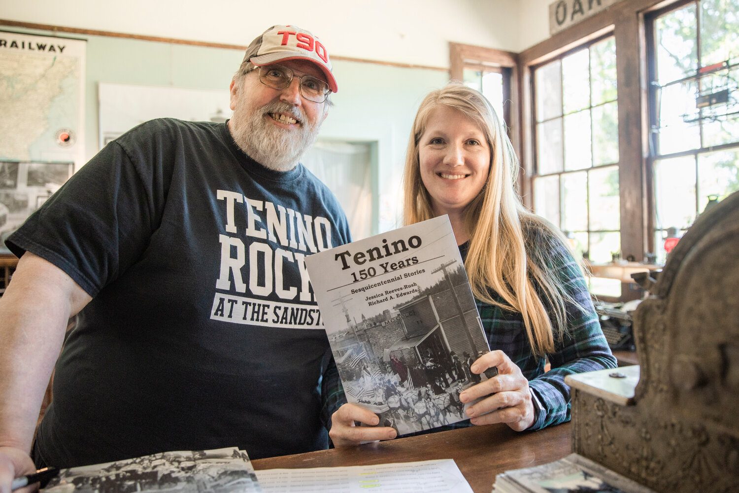 Tenino City Historian Richard Edwards and Tenino PARC (parks, arts, recreation and culture) Director Jessica Reeves-Rush smile for a photo in Tenino on Friday with their new, co-authored book celebrating the 150th birthday of the Stone City.