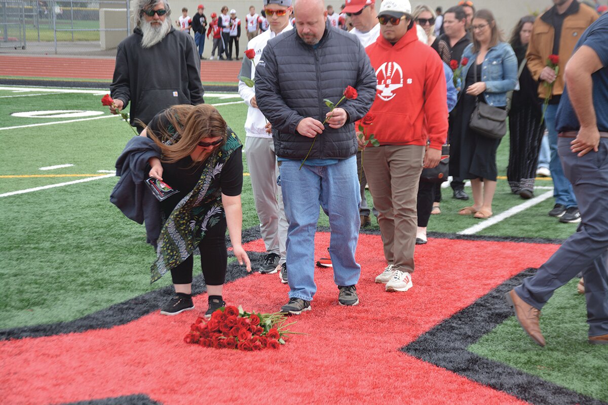 Attendees of a memorial service for Shawn Jemtegaard lay down roses in honor of the coach on May 21.