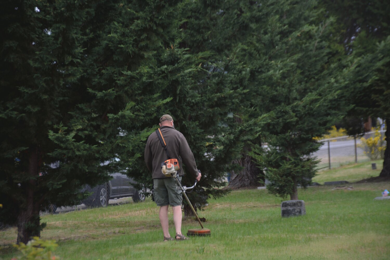 A volunteer weed whacks at the Roy Cemetery on Sunday, May 21.