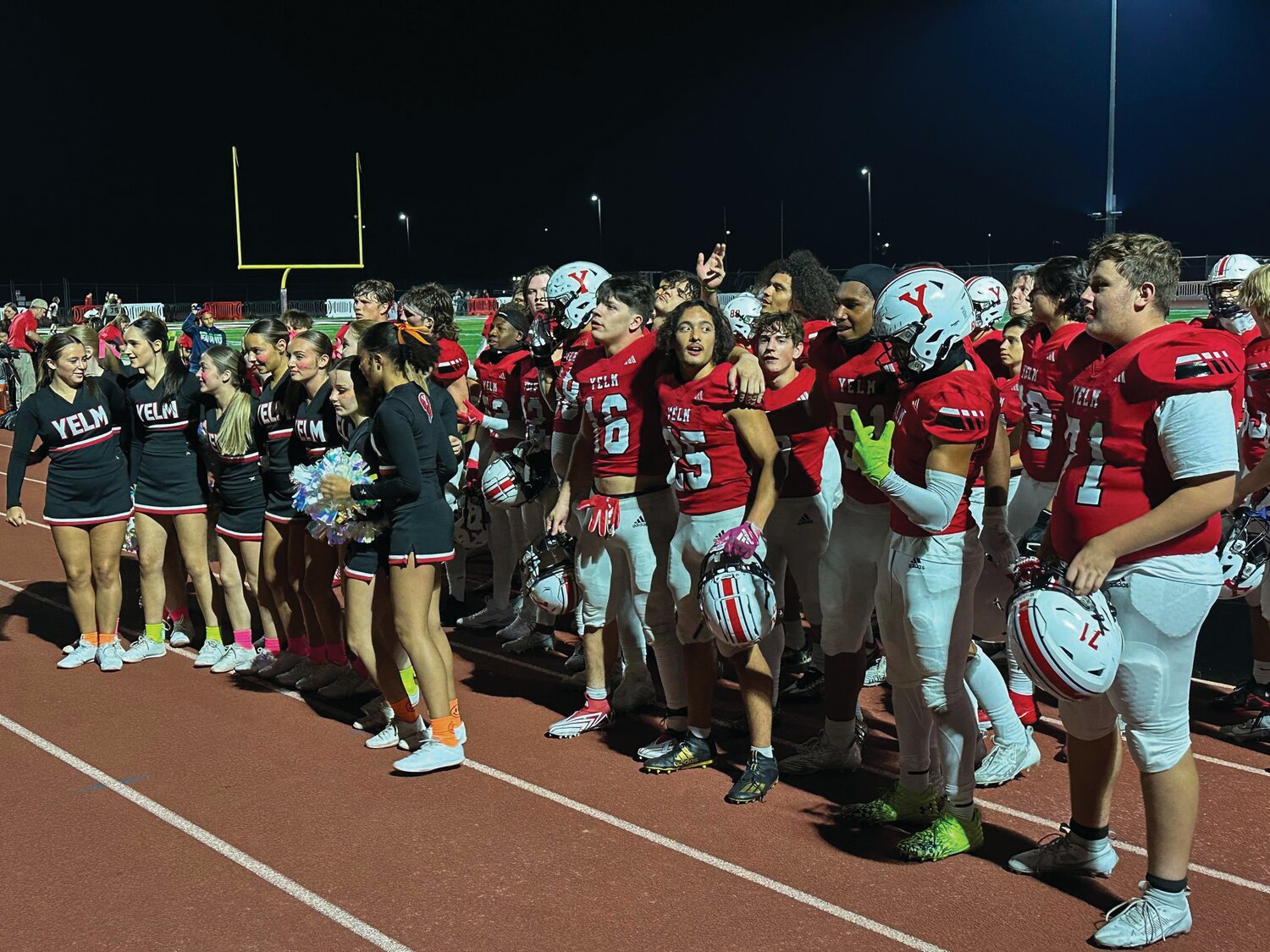 Members of the Yelm football and cheerleading teams join together to sing “Take Me Home, Country Roads” after the football team defeated River Ridge, 59-7.