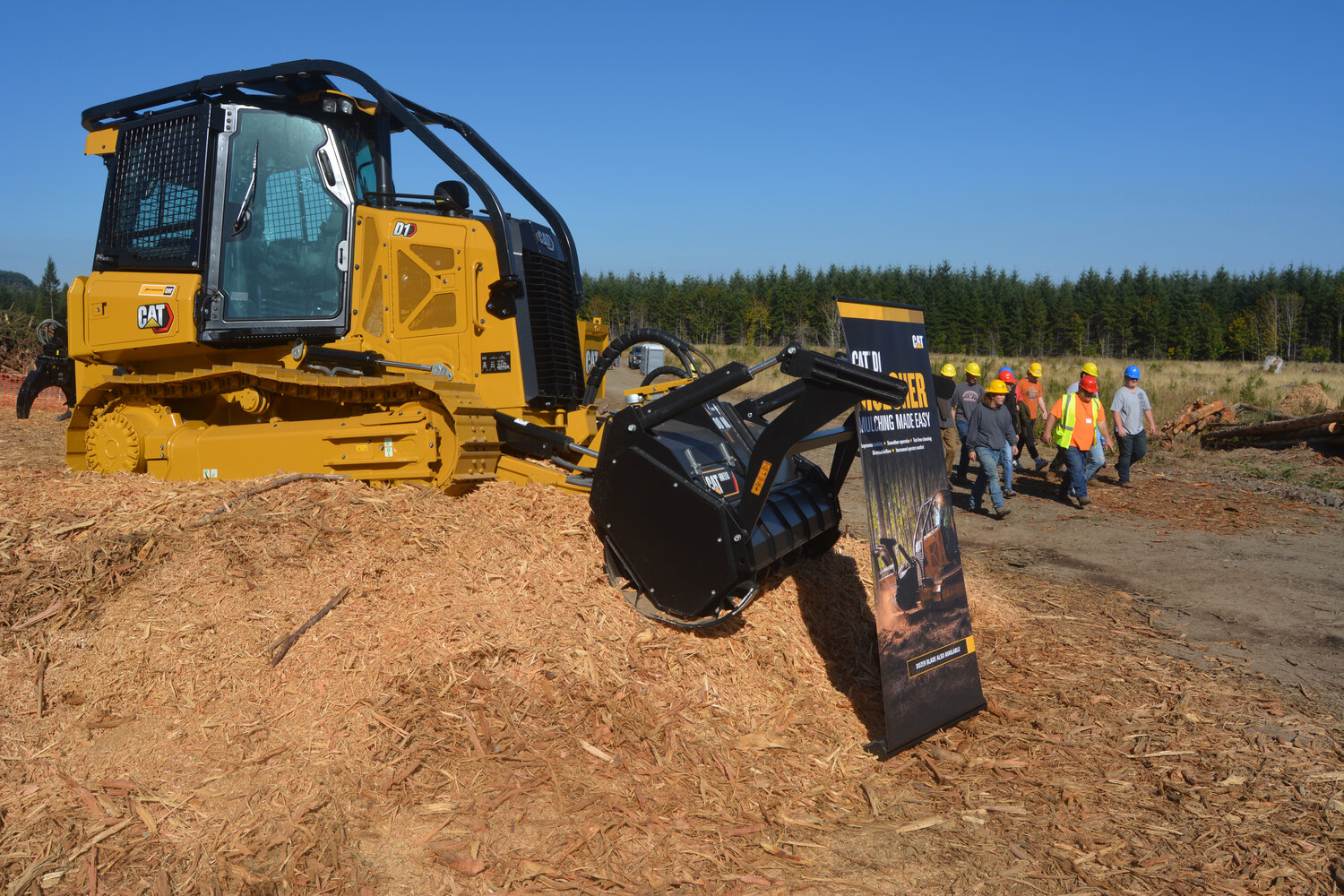 Students walk past a mulcher on display at the Pacific Logging Congress Live In-Woods Show on Sept. 22.
