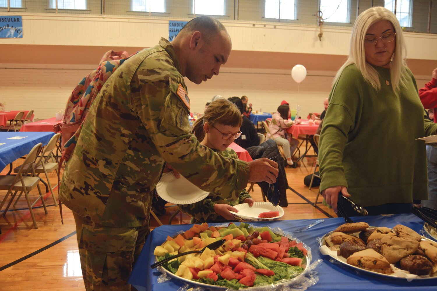 Sgt. First Class Ryan Lawless (left) helps himself to breakfast at Roy Elementary School on Nov. 9.