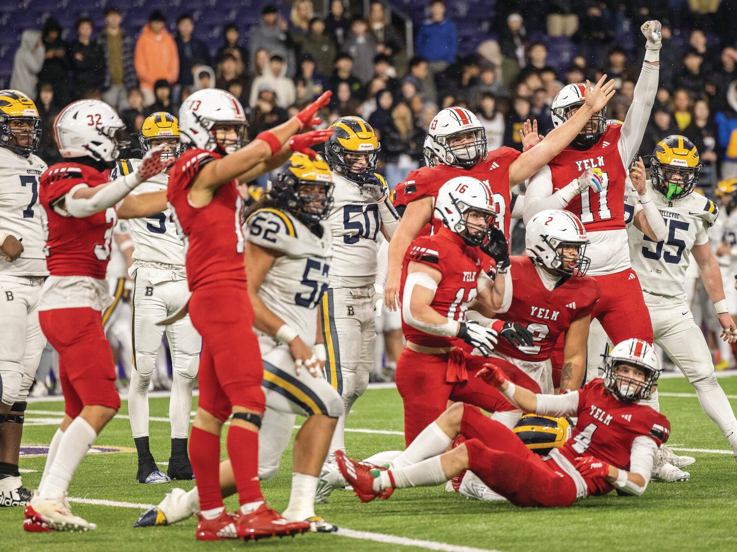 Yelm wide receiver Jordan Lasher (4) Is helped up off the ground as his teammates celebrate a turnover during the 3A state championship game at Husky Stadium on Friday, Dec. 1.