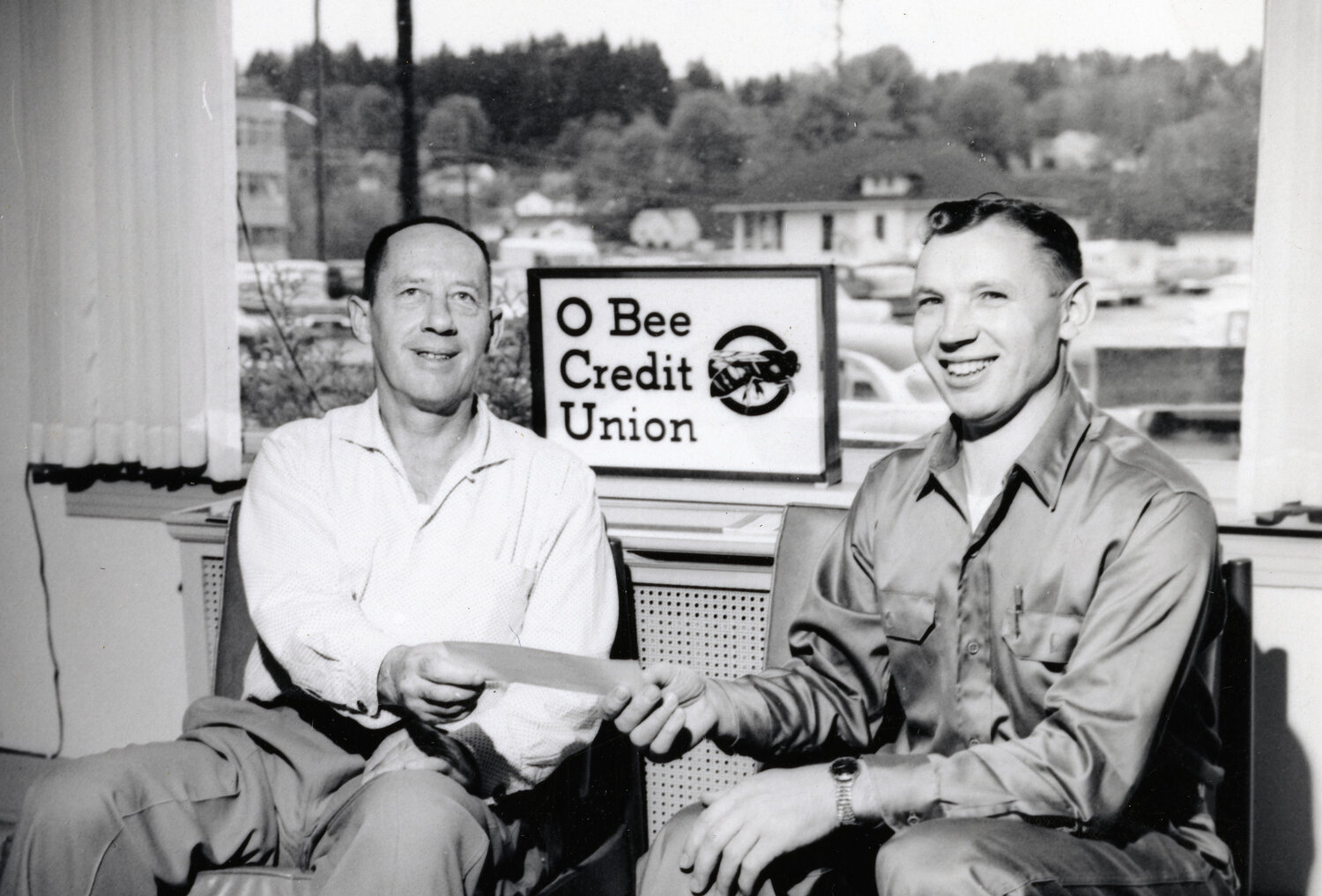 Ted McGill, left, is pictured with an O Bee Credit Union member in this photo provided by the credit union.