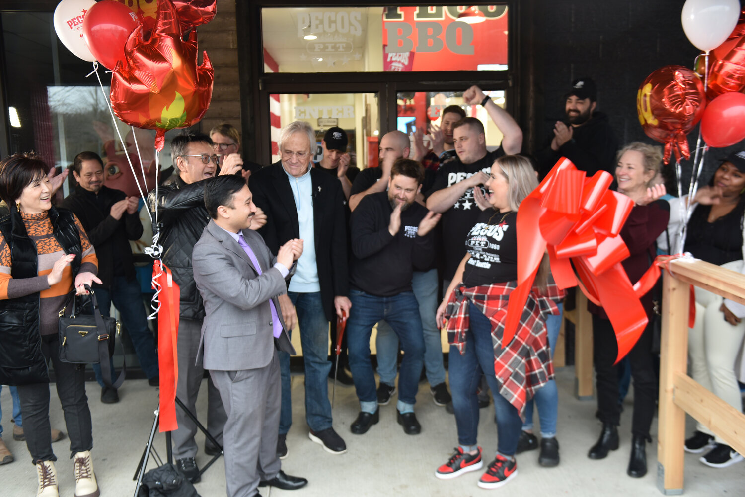 Attendants at Pecos Pit Bar-B-Que's grand opening in Yelm, including Mayor Joe DePinto and owner Gerry Kingen, smile and applaud after the ribbon was officially cut at the resturaunt on Friday, Jan. 26.